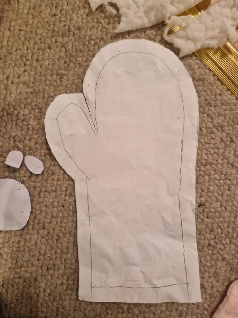 a paper pattern of the fluffy mitten made from tracing the outline of the mitten and adding 1.5 cm seam allowance